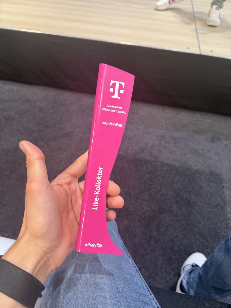 VonderWulf hält den pinken Like-Kollektor-Award von Telekom hilft in der Hand